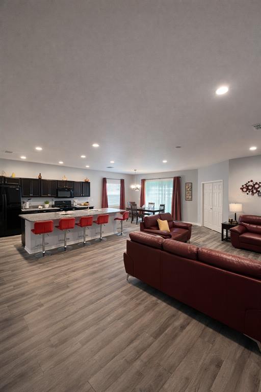 An open-concept kitchen and living area features dark cabinetry, a breakfast bar, and red furniture — 446 GLENKIRK WAY, LAKE ALFRED, FL