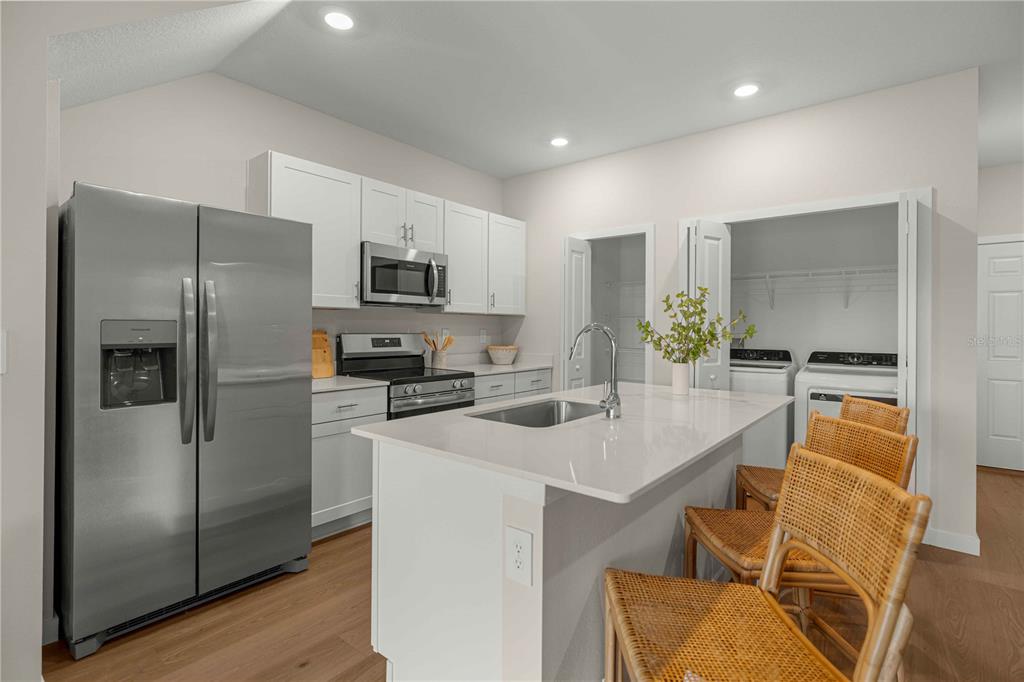 A kitchen features white cabinets, stainless steel appliances, a center island, and an adjacent laundry closet — 4968 SW 83RD PLACE, OCALA, FL