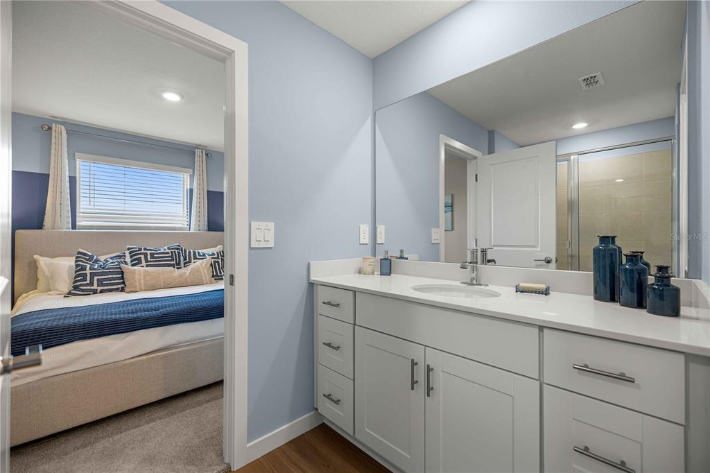 A bathroom with a white vanity and mirror connects to a bedroom with a bed — 4968 SW 83RD PLACE, OCALA, FL