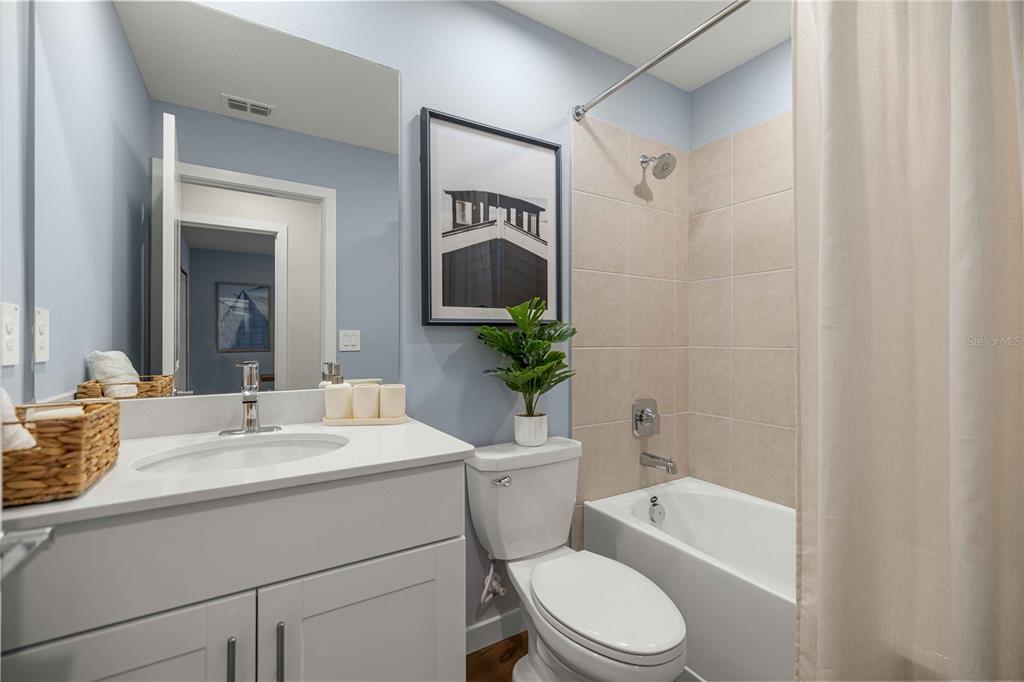 A bathroom features a white vanity, a toilet, and a shower-tub combination with beige tiles — 4968 SW 83RD PLACE, OCALA, FL