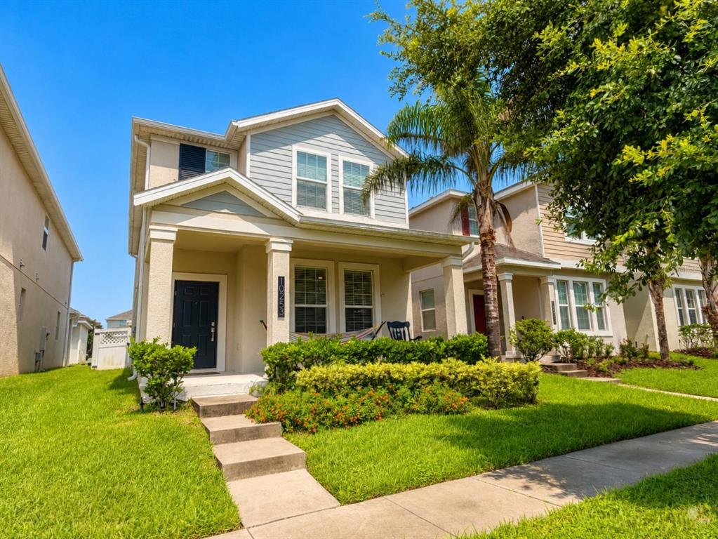 A two-story house with a front porch, light-colored siding, and a landscaped front yard — 10253 LOVE STORY STREET, WINTER GARDEN, FL
