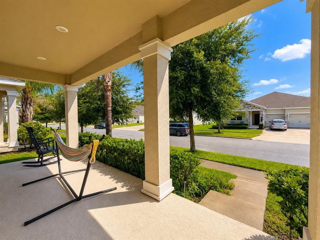 A covered porch features a hammock, a rocking chair, and a view of the street — 10253 LOVE STORY STREET, WINTER GARDEN, FL