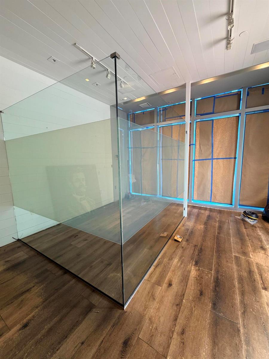 A room under construction features a glass-walled enclosure, wood flooring, and windows covered with paper — 6801 Collins Avenue # 1215, Miami Beach FL 33141, MIAMI BEACH, FL