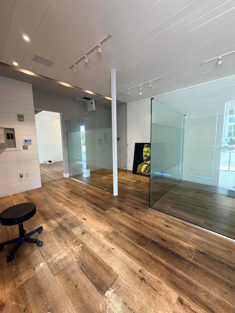 An interior view shows a room with wood flooring, glass partitions, and a portrait painting — 6801 Collins Avenue # 1215, Miami Beach FL 33141, MIAMI BEACH, FL