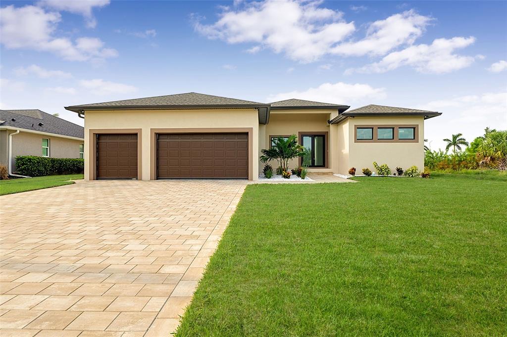 A single-story house with a beige exterior, a three-car garage, and a paved driveway — 15618 VISCOUNT CIRCLE, PORT CHARLOTTE, FL