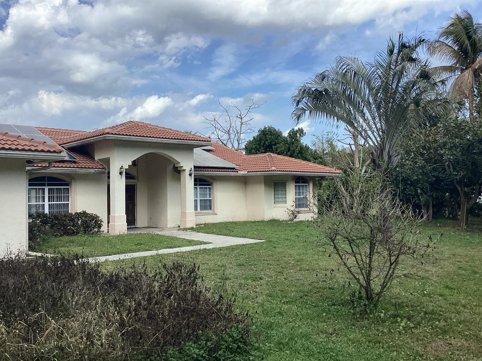 A single-story house with a tiled roof, arched entryway, and a front lawn — 12173 N 88th Pl Place N # 1, FL 33412, FL
