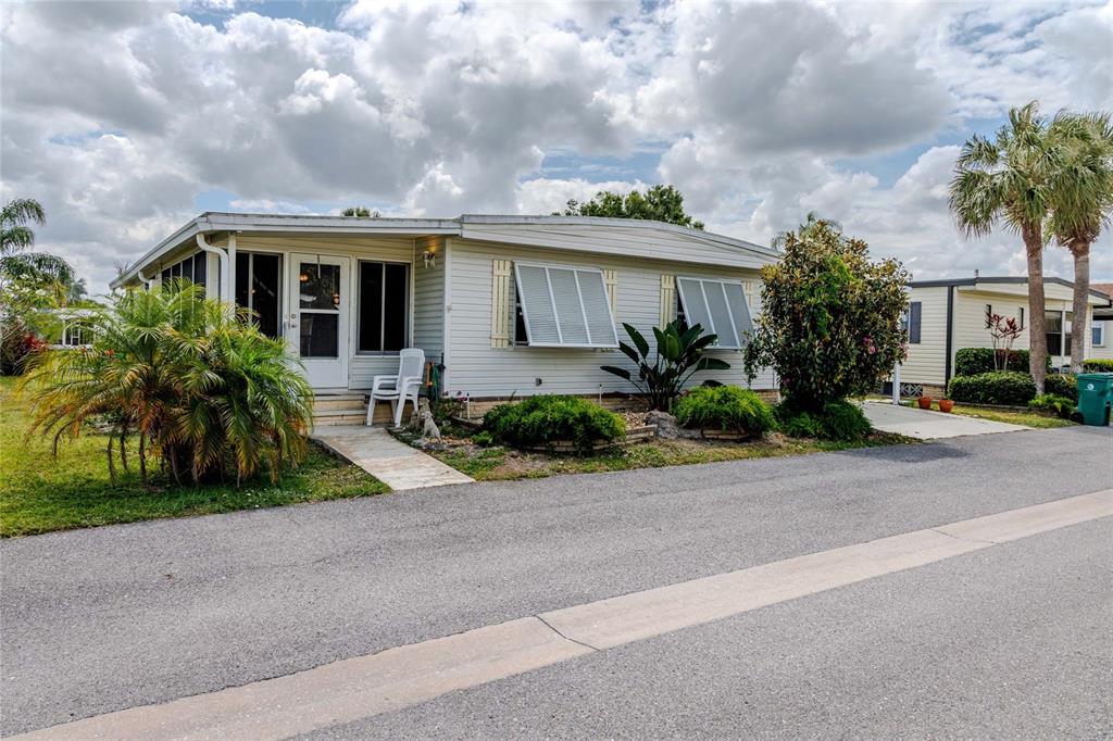 A single-story mobile home with light siding, white shutters, and a small front porch — 2100 KINGS HIGHWAY UNIT 969, PORT CHARLOTTE, FL