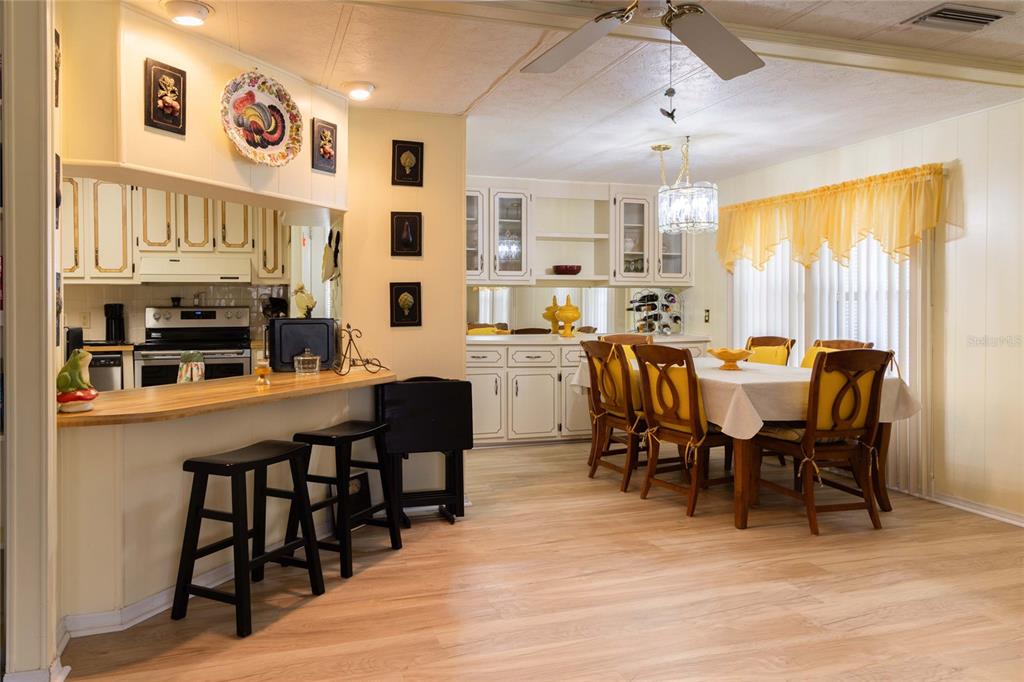 A kitchen with a breakfast bar and stools opens into a dining area with seating — 2100 KINGS HIGHWAY UNIT 969, PORT CHARLOTTE, FL