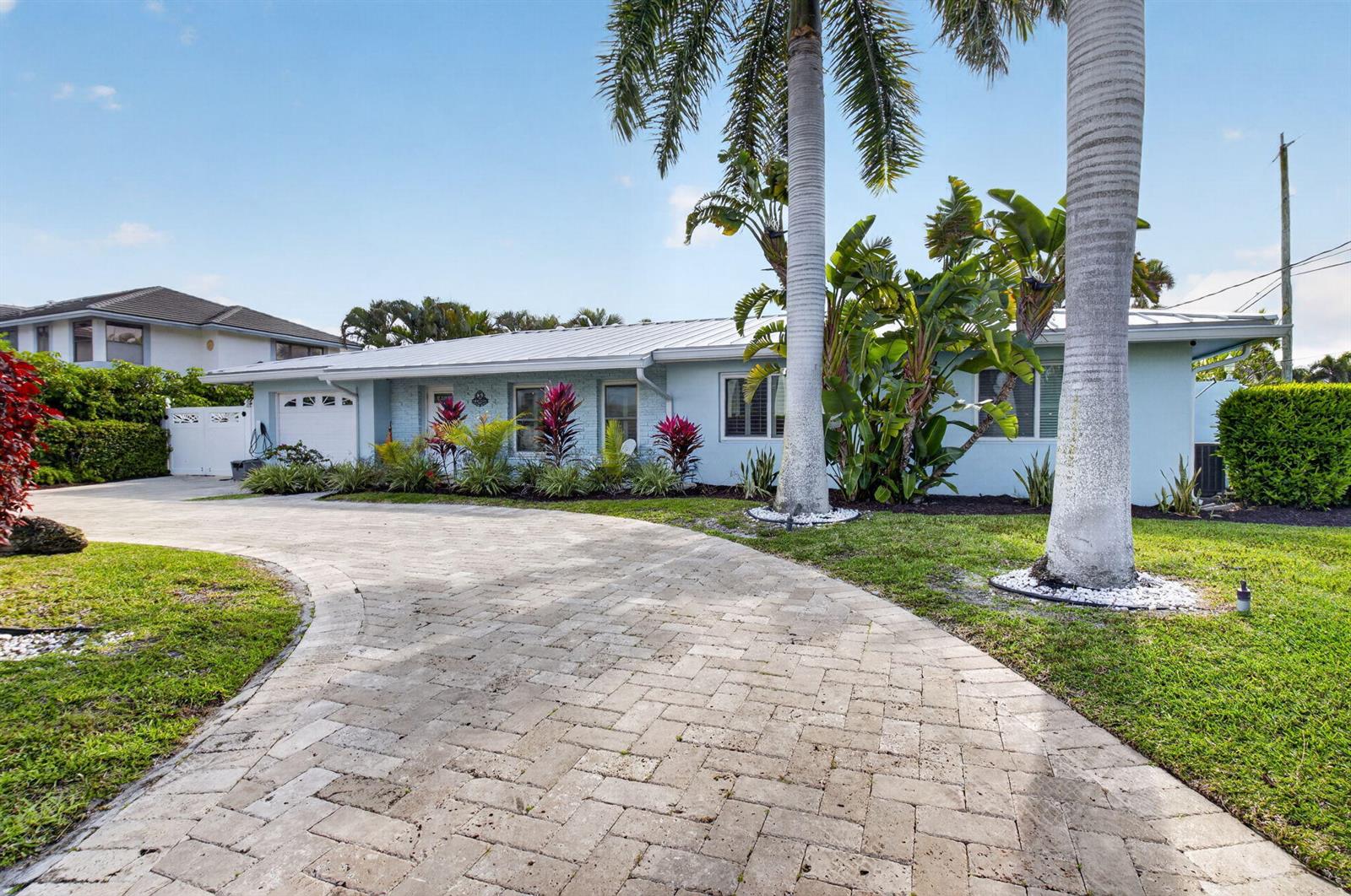 A light blue single-story house with a paved driveway and palm trees in the front yard — 5800 NE 7th Avenue, Boca Raton FL 33487, BOCA RATON, FL