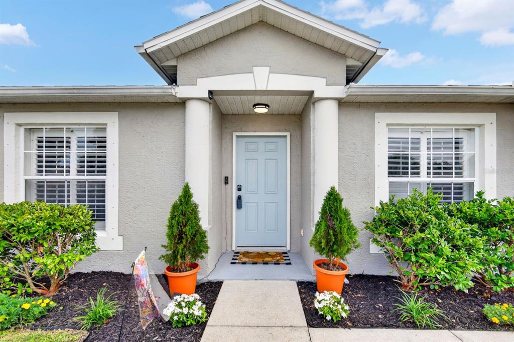 The exterior of a house features a light blue front door flanked by two potted trees — 4394 CUTHBERT AVENUE, NORTH PORT, FL