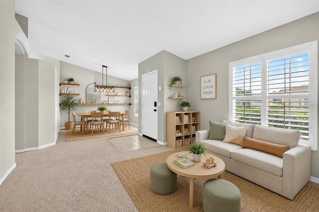 A living room with beige carpet, a light-colored sofa, and an adjacent dining area — 4394 CUTHBERT AVENUE, NORTH PORT, FL