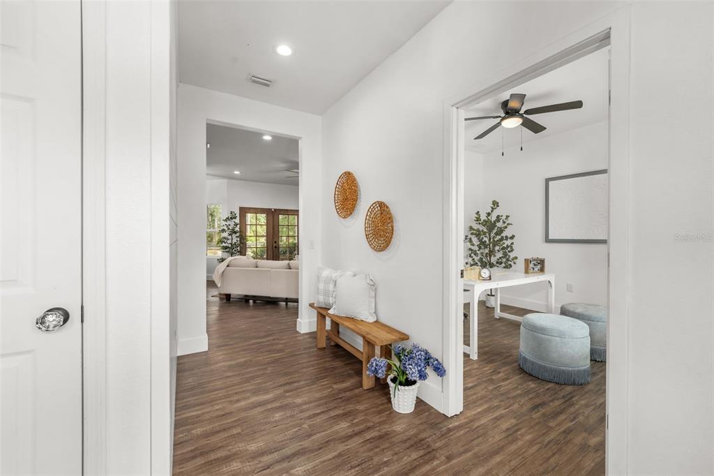 A hallway with wood-look flooring leads to a living area and an adjacent home office — 15971 SE 64TH STREET, LAKE BUTLER, FL