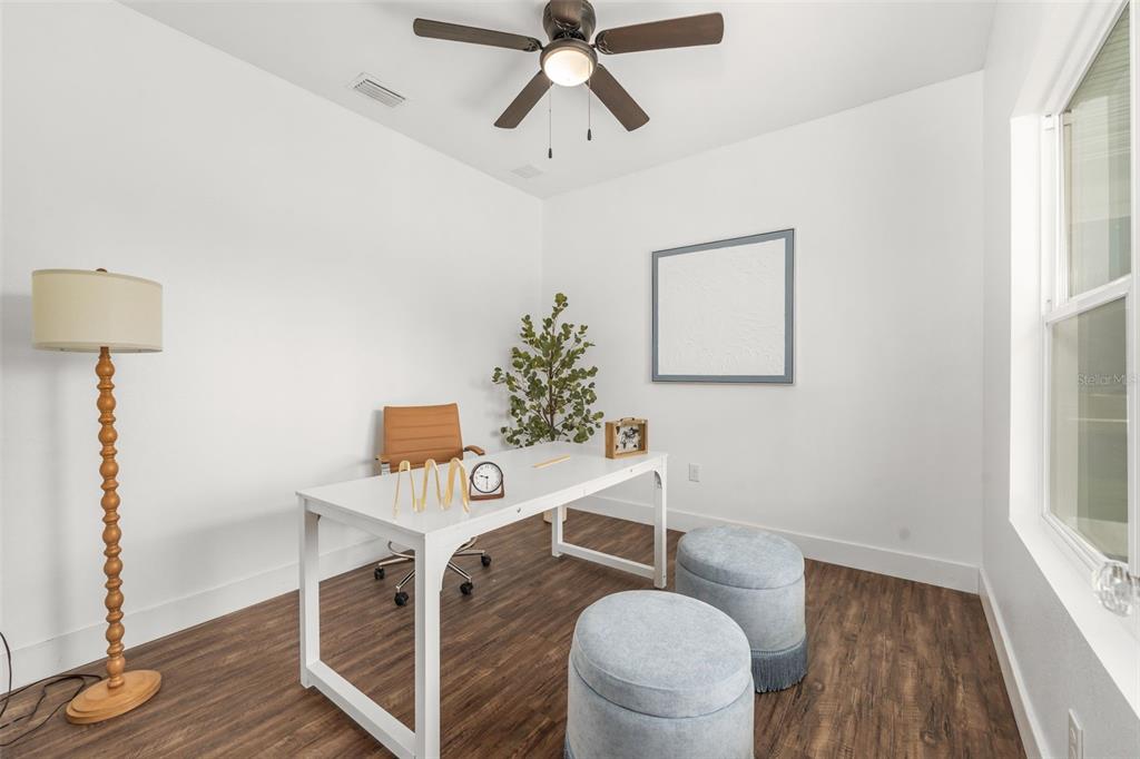 A home office features a white desk, two blue ottomans, and a floor lamp — 15971 SE 64TH STREET, LAKE BUTLER, FL