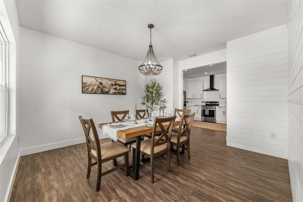 A dining room with a wooden table, chairs, a chandelier, and a view into the kitchen — 15971 SE 64TH STREET, LAKE BUTLER, FL