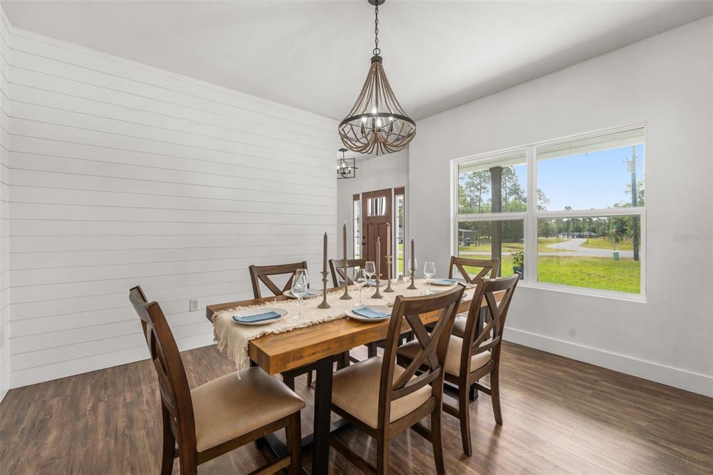 A dining room features a wooden table, shiplap wall, and a rustic chandelier — 15971 SE 64TH STREET, LAKE BUTLER, FL
