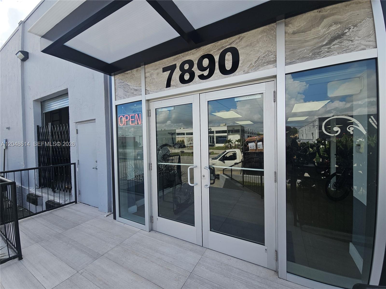 The exterior entrance of a commercial building features glass double doors and the number 7890 — 7890 NW 34th St, Doral FL 33122, DORAL, FL