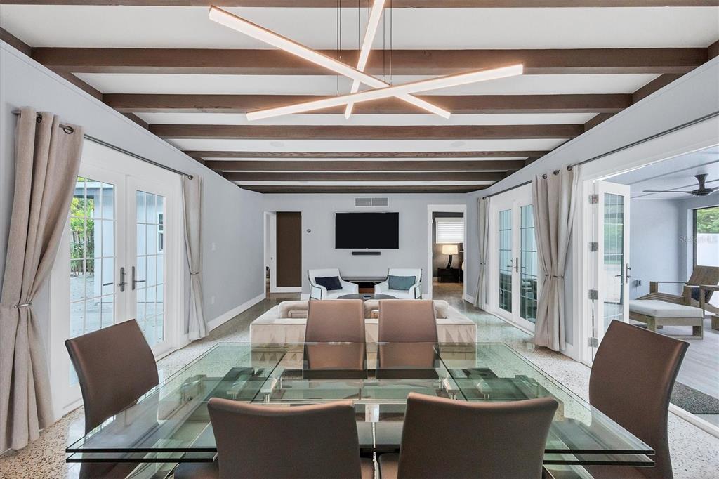 A dining area with a glass table leads into a living room with exposed beams — 1116 WESTWAY DRIVE, SARASOTA, FL
