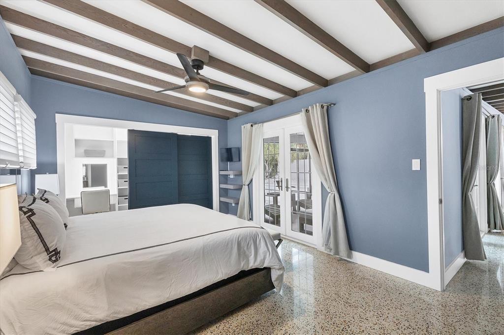 A bedroom with blue walls, exposed ceiling beams, a ceiling fan, and terrazzo flooring — 1116 WESTWAY DRIVE, SARASOTA, FL
