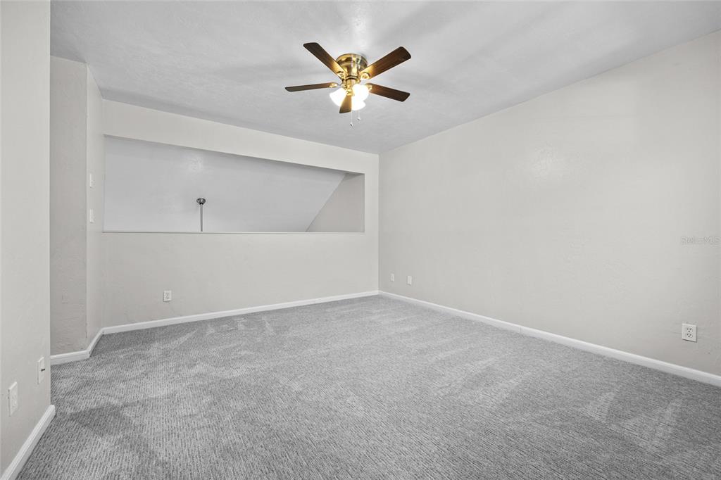 An empty bedroom features gray carpet, light-colored walls, a ceiling fan, and a recessed wall niche — 7018 NW 52ND TERRACE, GAINESVILLE, FL