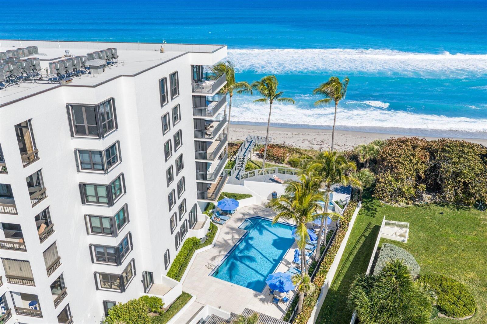 An exterior view of a multi-story white apartment building with balconies overlooking a waterway — 19750 S Beach Road # 7050, Jupiter FL 33469, JUPITER, FL