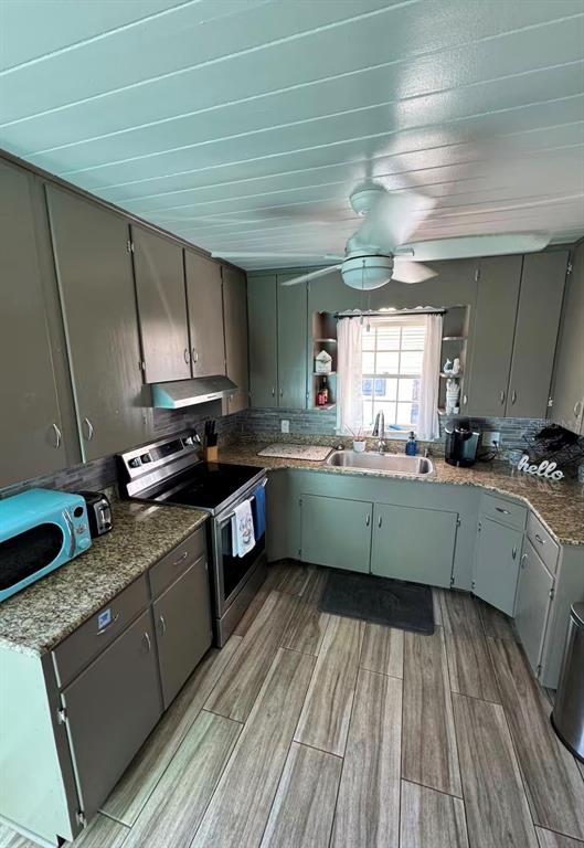A kitchen features gray cabinets, granite countertops, a stainless steel stove, and wood-look tile flooring — 1564 S MICHIGAN AVENUE, CLEARWATER, FL