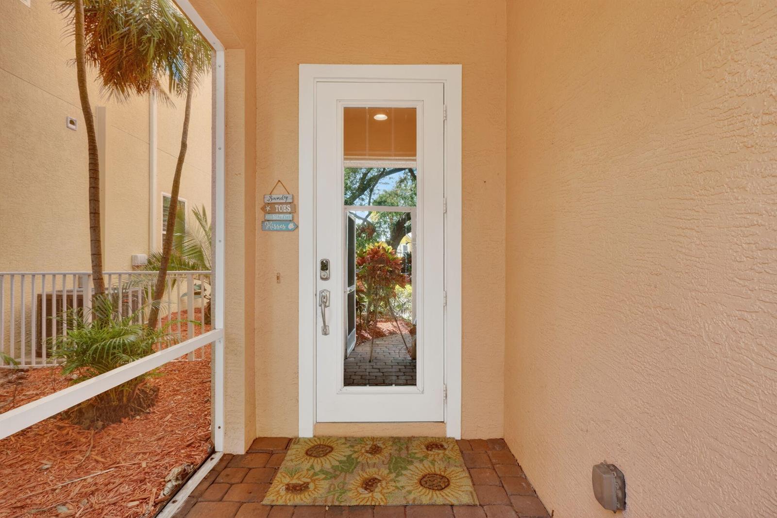 A white front door with a glass insert sits on a brick porch with a mat — 540 SW Akron Avenue, Stuart FL 34994, STUART, FL