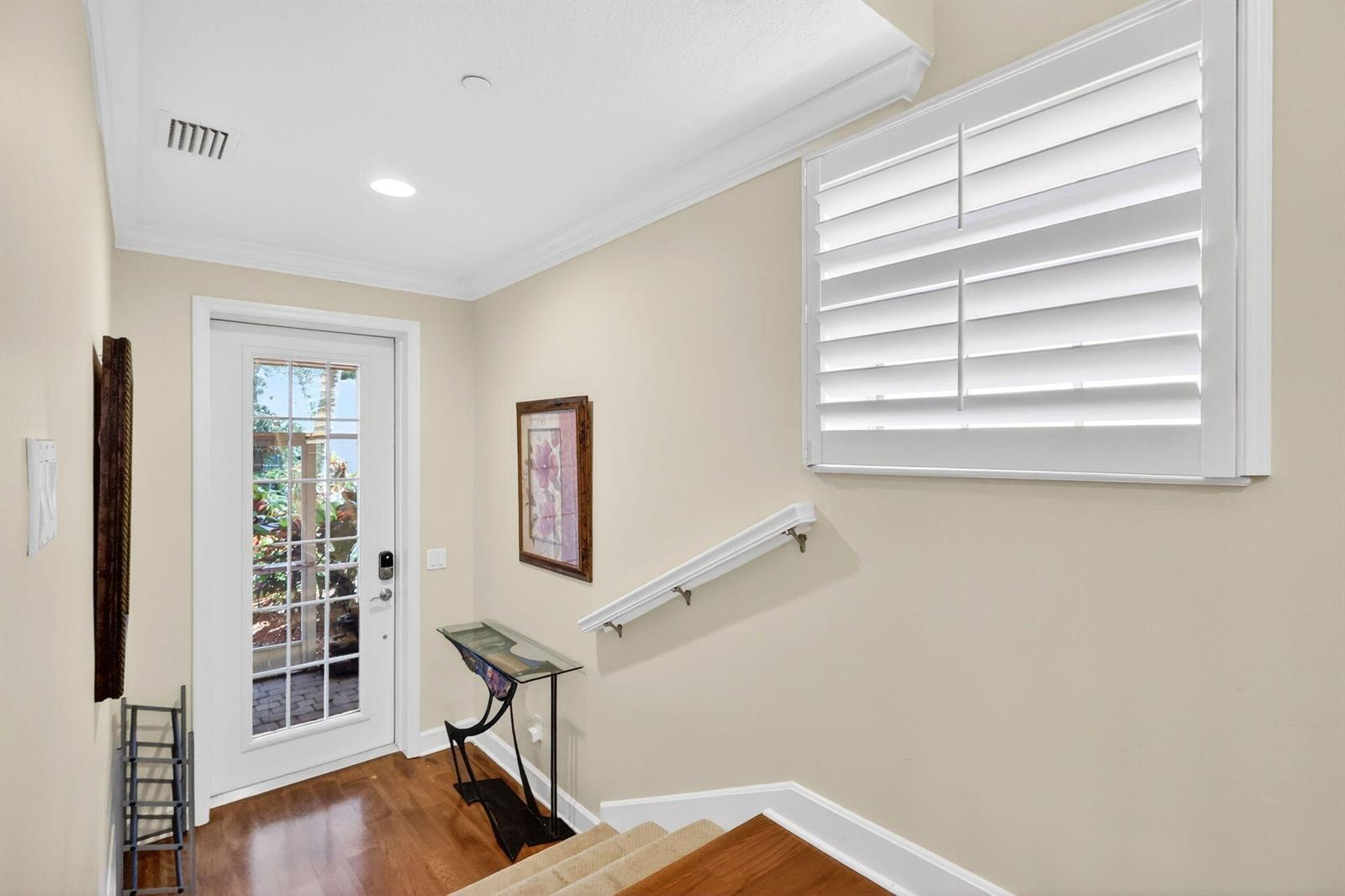 An entryway features a white door, a glass console table, and a staircase with railing — 540 SW Akron Avenue, Stuart FL 34994, STUART, FL