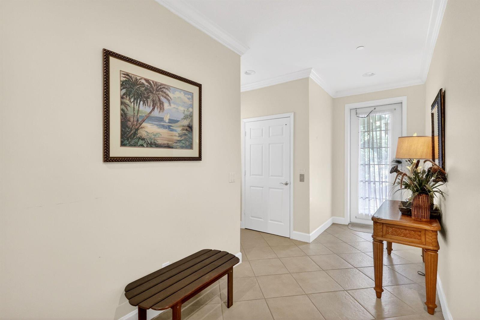 A tiled entryway features a wooden bench, a console table with a lamp, and artwork — 540 SW Akron Avenue, Stuart FL 34994, STUART, FL