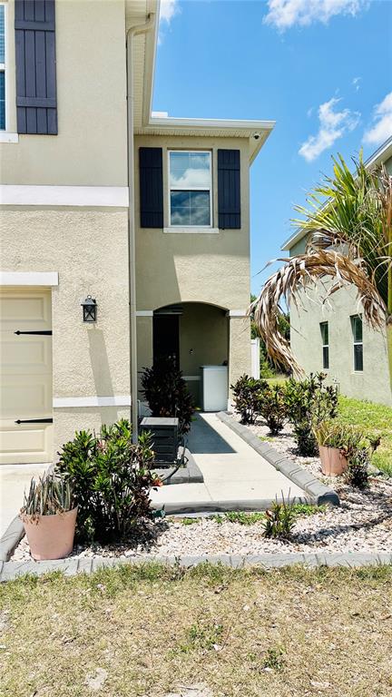 A tan two-story house features a side entrance, dark shutters, and a landscaped walkway — 11152 LELAND GROVES DRIVE, RIVERVIEW, FL