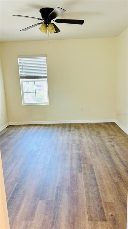 An empty room features light-colored walls, a ceiling fan, a window with blinds, and wood-look flooring — 11152 LELAND GROVES DRIVE, RIVERVIEW, FL