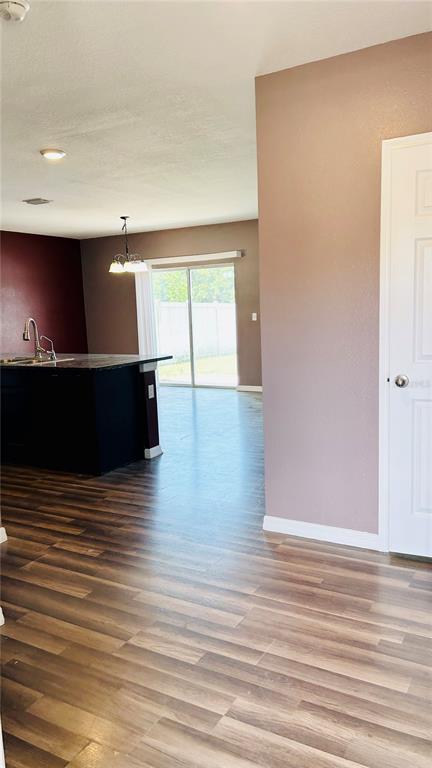 A kitchen with a dark island and wood-look flooring opens to a bright living area — 11152 LELAND GROVES DRIVE, RIVERVIEW, FL