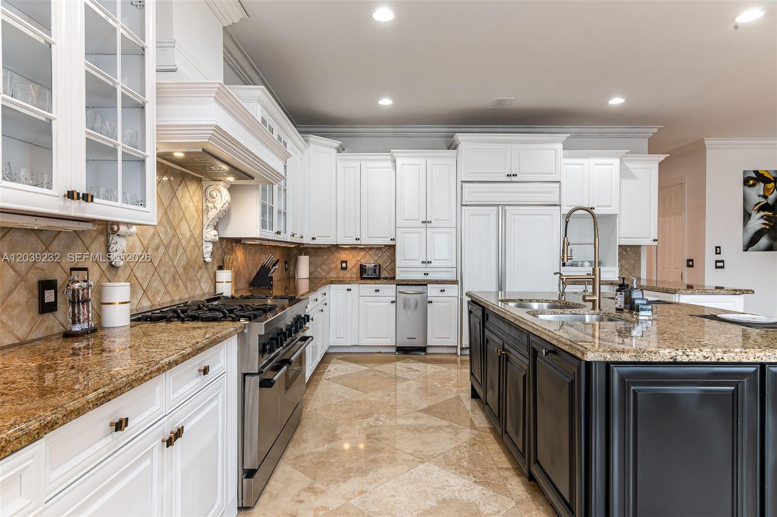 A kitchen features white cabinetry, a dark island, granite countertops, and stainless steel appliances — FORT LAUDERDALE, FL