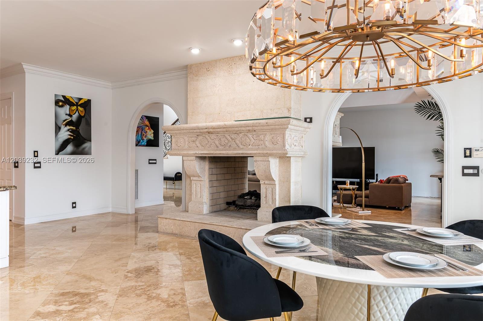 A dining area features a round marble table, black chairs, and a large stone fireplace — FORT LAUDERDALE, FL