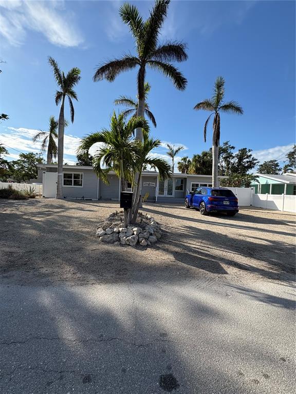 A blue SUV is parked in front of a gray house with palm trees — 5032 CALLE MINORGA, SARASOTA, FL