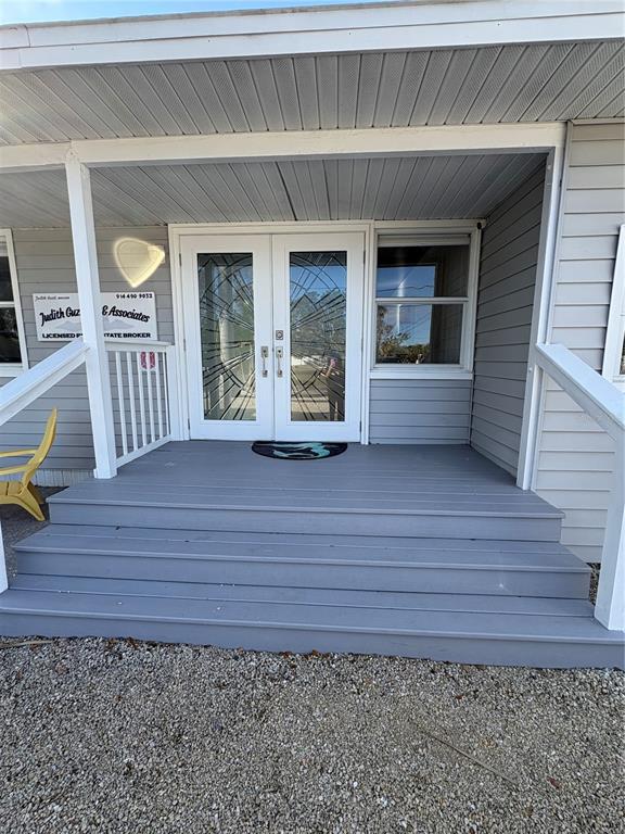 A gray wooden porch with steps leads to double glass doors with decorative metal grilles — 5032 CALLE MINORGA, SARASOTA, FL