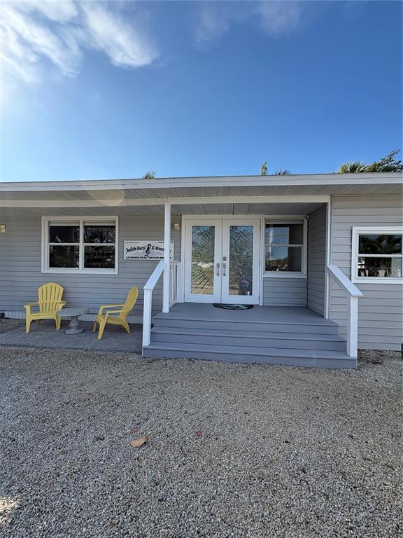 The exterior of a gray building features a double-door entrance, stairs, and two yellow chairs — 5032 CALLE MINORGA, SARASOTA, FL
