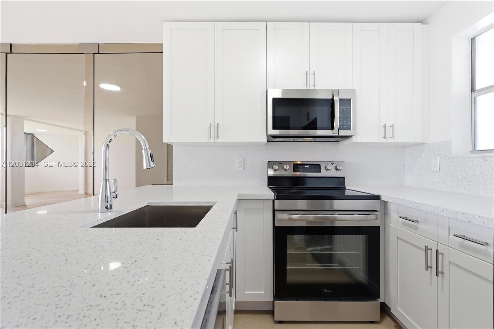 A modern kitchen features white cabinetry, stainless steel appliances, and speckled white quartz countertops — 2950 SW 3rd Ave # 7F, Miami FL 33129, MIAMI, FL