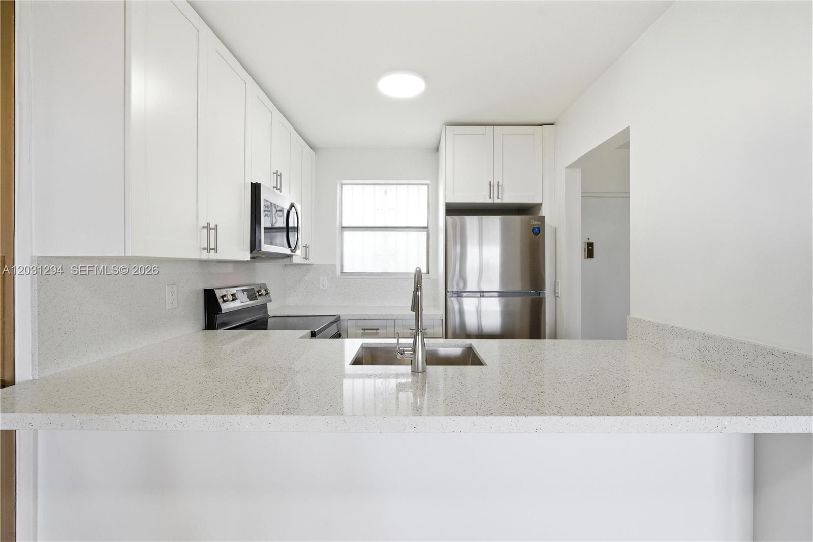 A kitchen features white cabinets, stainless steel appliances, and a speckled white countertop — 2950 SW 3rd Ave # 7F, Miami FL 33129, MIAMI, FL