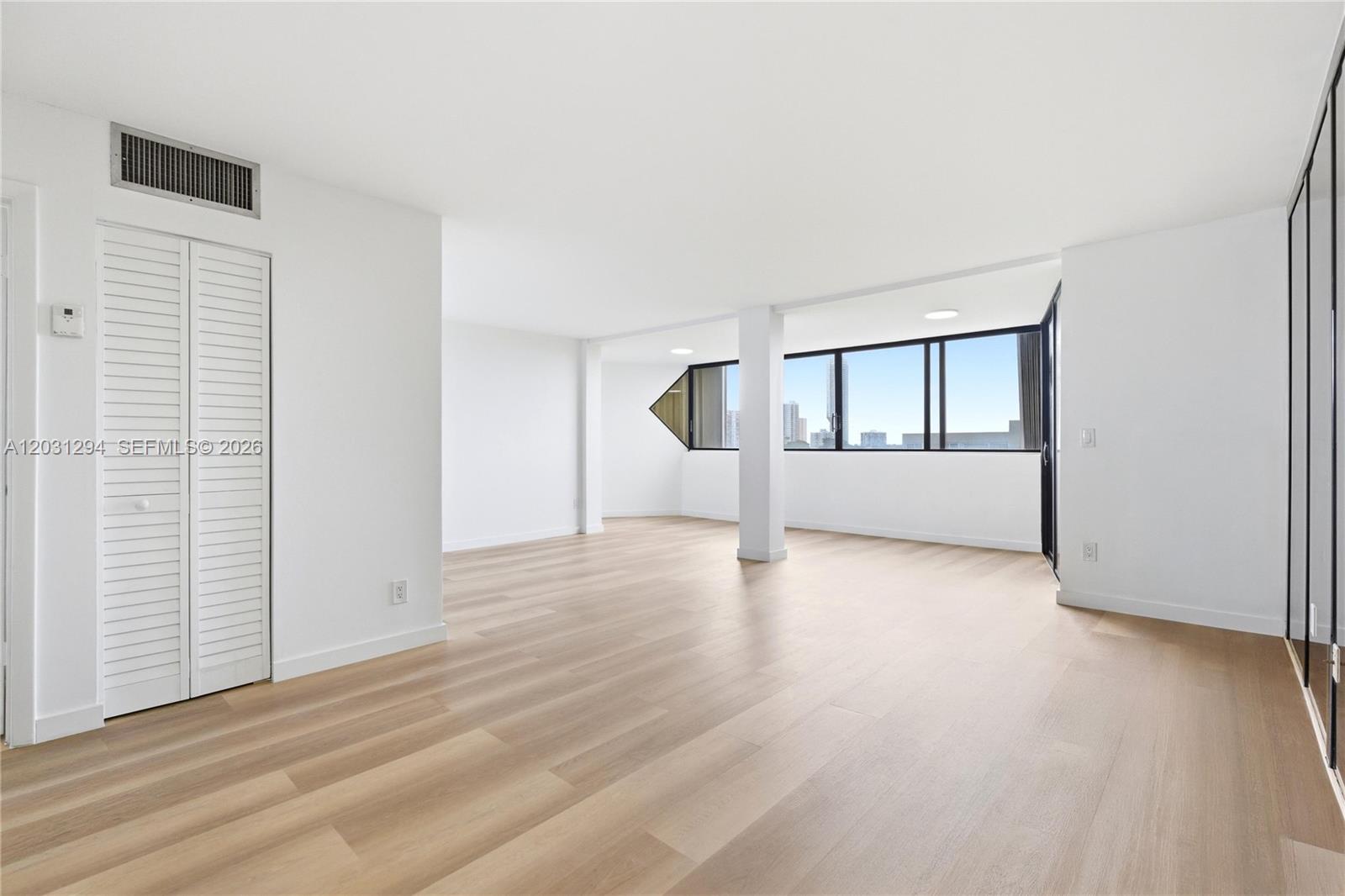 An empty room with light wood floors, white walls, and large windows overlooking a city — 2950 SW 3rd Ave # 7F, Miami FL 33129, MIAMI, FL
