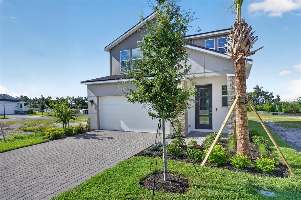 A two-story house with a paved driveway, a white garage door, and a palm tree — 1775 SOARING VIDA STREET, PALMETTO, FL