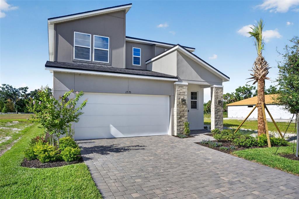 A two-story house with a white garage door, stone accents, and a paved driveway — 1775 SOARING VIDA STREET, PALMETTO, FL