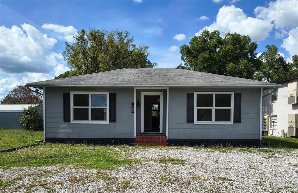 A gray, single-story house with a gravel driveway and a small red-brick front step — 1628 E GARY ROAD, LAKELAND, FL