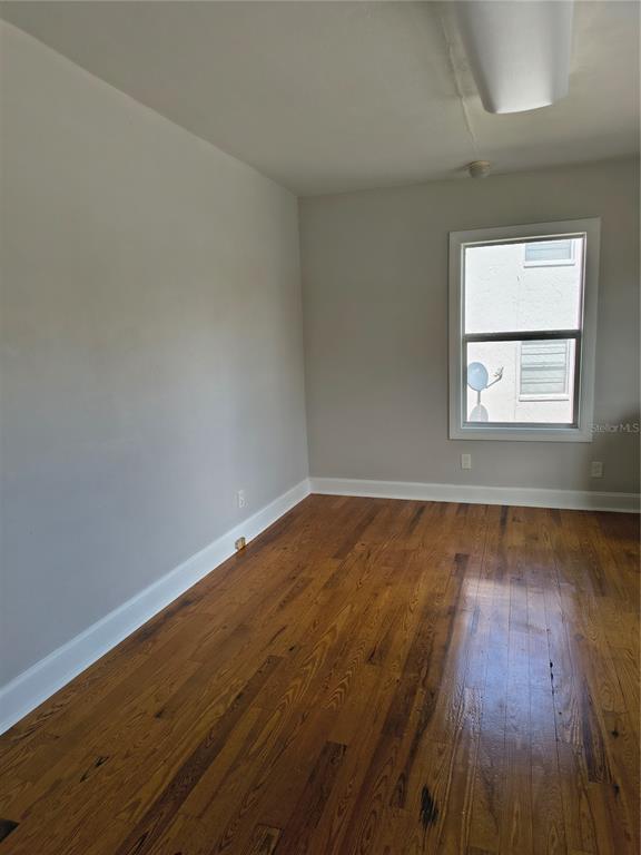 An empty room features hardwood floors, light gray walls, and a single window — 1628 E GARY ROAD, LAKELAND, FL