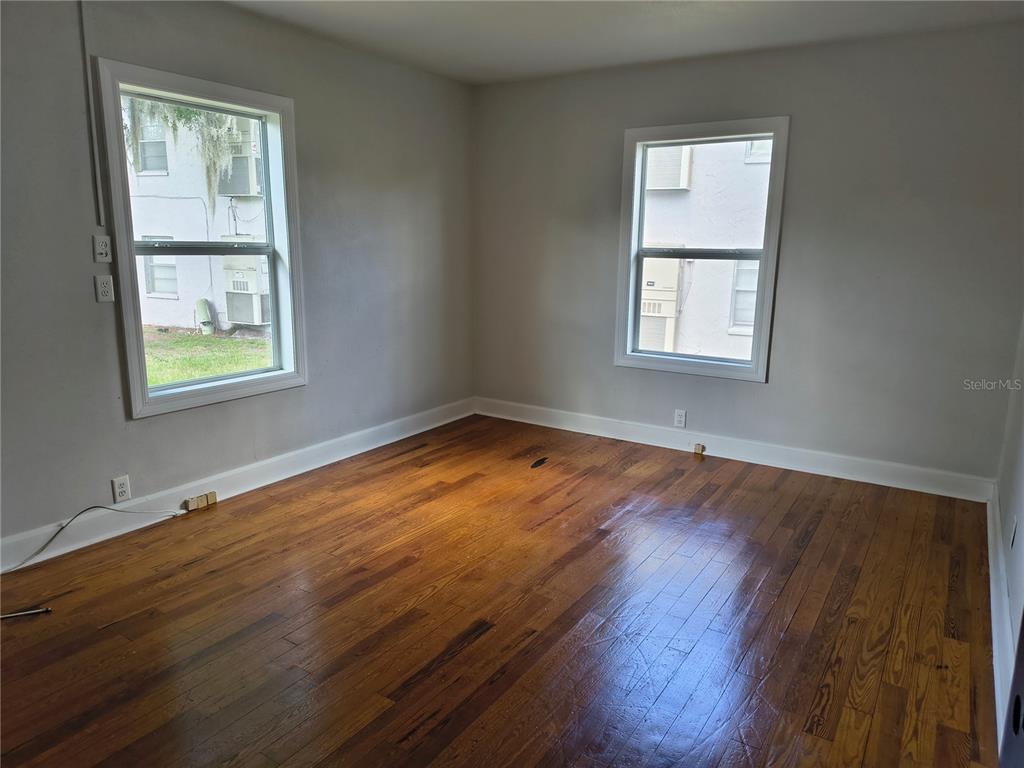 An empty room features hardwood floors, light gray walls, and two windows — 1628 E GARY ROAD, LAKELAND, FL