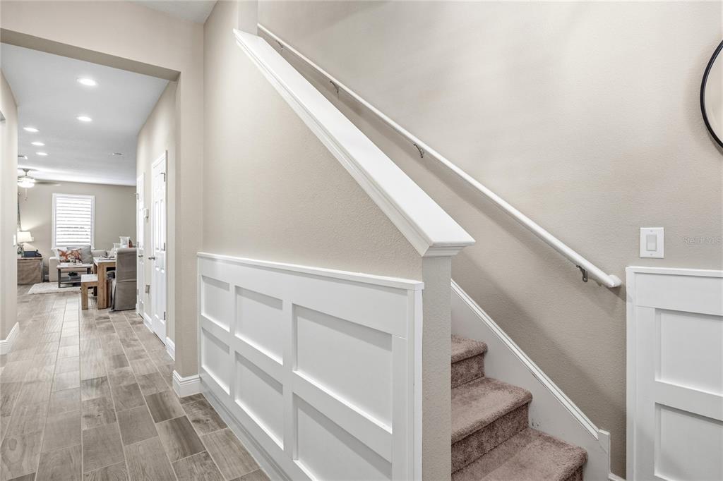 A staircase with carpeted steps and white wainscoting leads upward from a tiled hallway — 18892 ULMUS STREET, LUTZ, FL