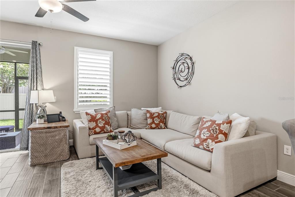A living room features a beige sectional sofa, a wooden coffee table, and tile flooring — 18892 ULMUS STREET, LUTZ, FL