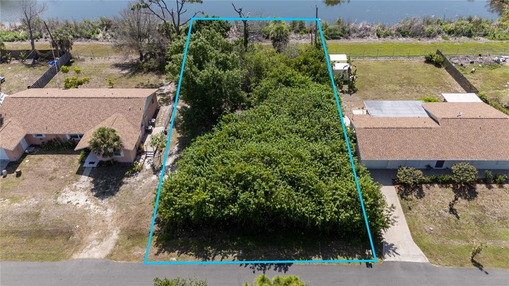 An aerial view shows a vacant, tree-covered residential lot situated between two houses — 1845 SHADOW LANE, ENGLEWOOD, FL