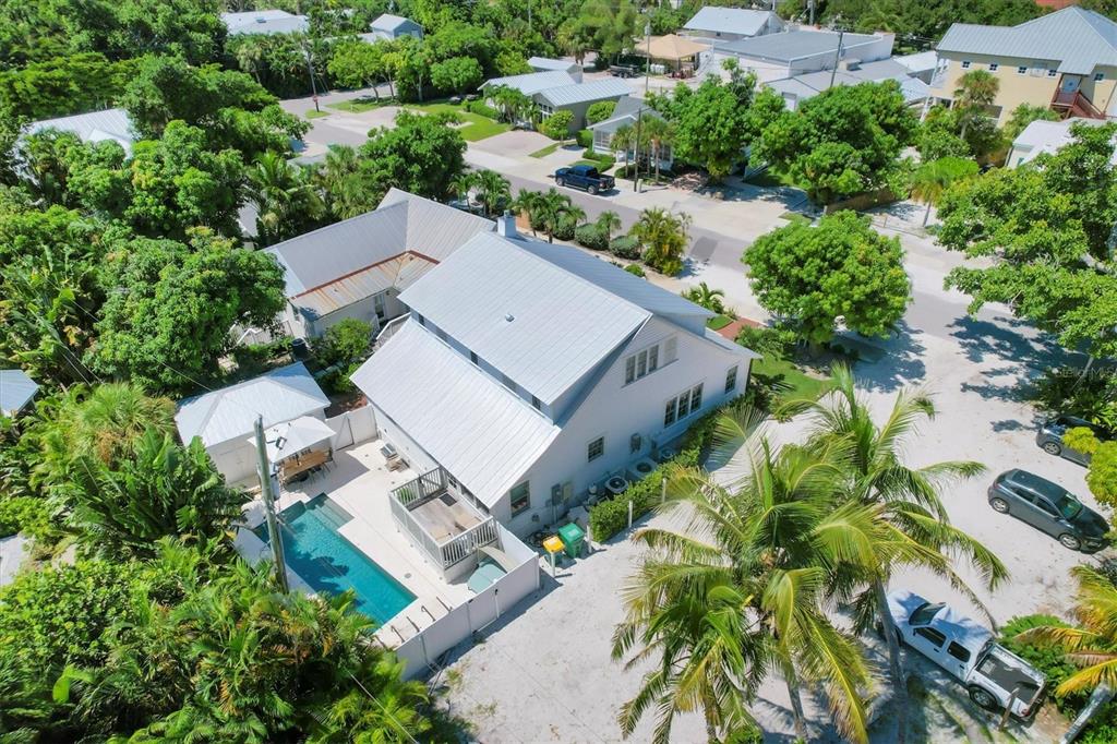 An aerial view of a white house with a metal roof, pool, and surrounding trees — 342 PALM AVENUE, BOCA GRANDE, FL