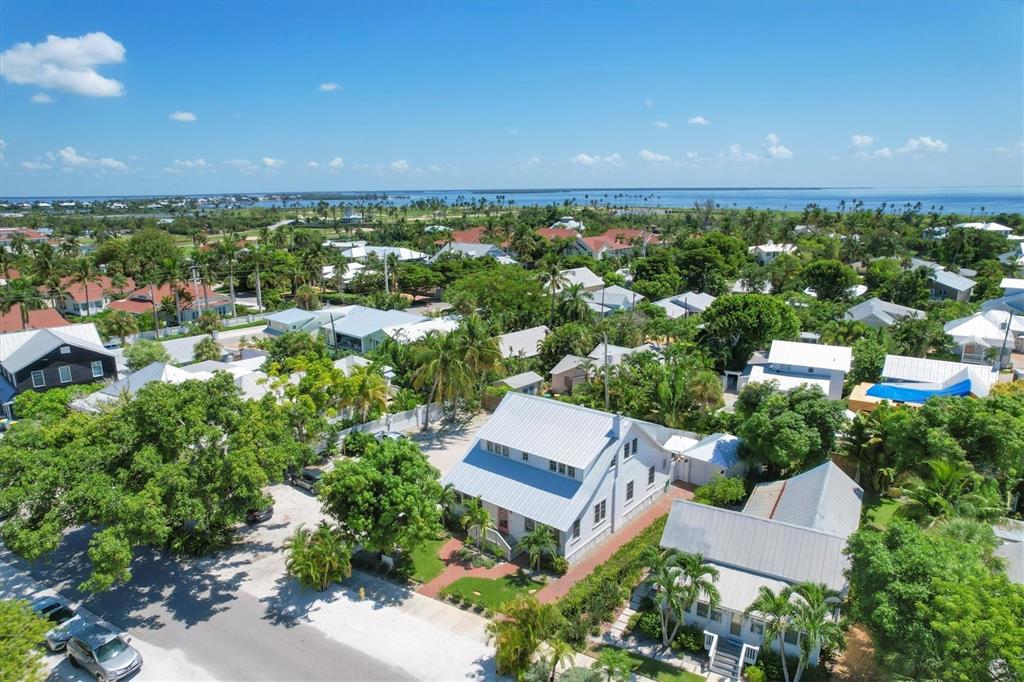 An aerial view shows a white house with a metal roof surrounded by lush trees — 342 PALM AVENUE, BOCA GRANDE, FL