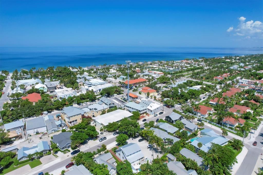 An aerial view shows a coastal town with houses, lush trees, and the ocean beyond — 342 PALM AVENUE, BOCA GRANDE, FL